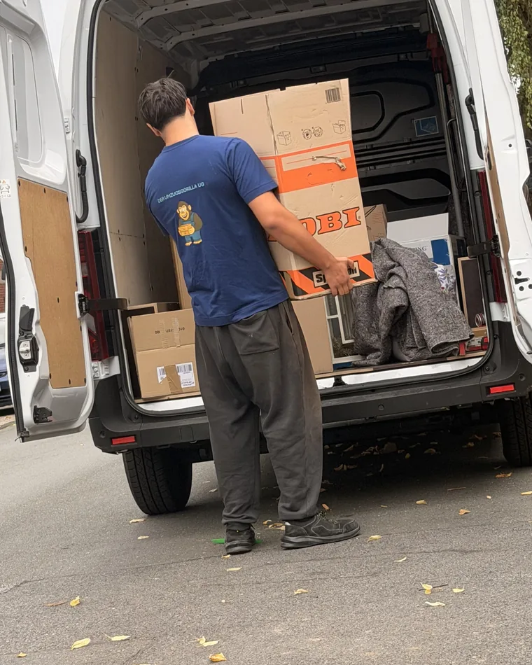 Ein Mitarbeiter belädt den Umzugswagen mit beschrifteten Kartons